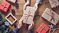 Two Holiday Volunteers Pass a Wrapped Gift to Each Other Across the Table