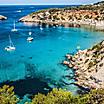 Boats anchored off a secluded beach in Es Verda Island, Ibiza, Spain