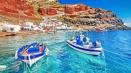 Beautiful landscape of two fishing boats anchored in blue water at the old port in Oia, Santorini, Greece