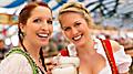 Young women in traditional Bavarian clothes - dirndl or tracht - on a festival or Oktoberfest in a beer tent