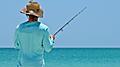 An unidentified local young man on the beach fishing in the shallow water of the Gulf of Mexico.  